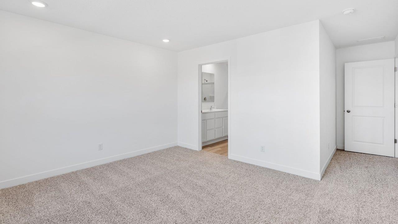 whispering pines portsmouth primary bedroom with elk beige carpet, white walls, 2 windows, and ensuite bathroom and walk-in closet