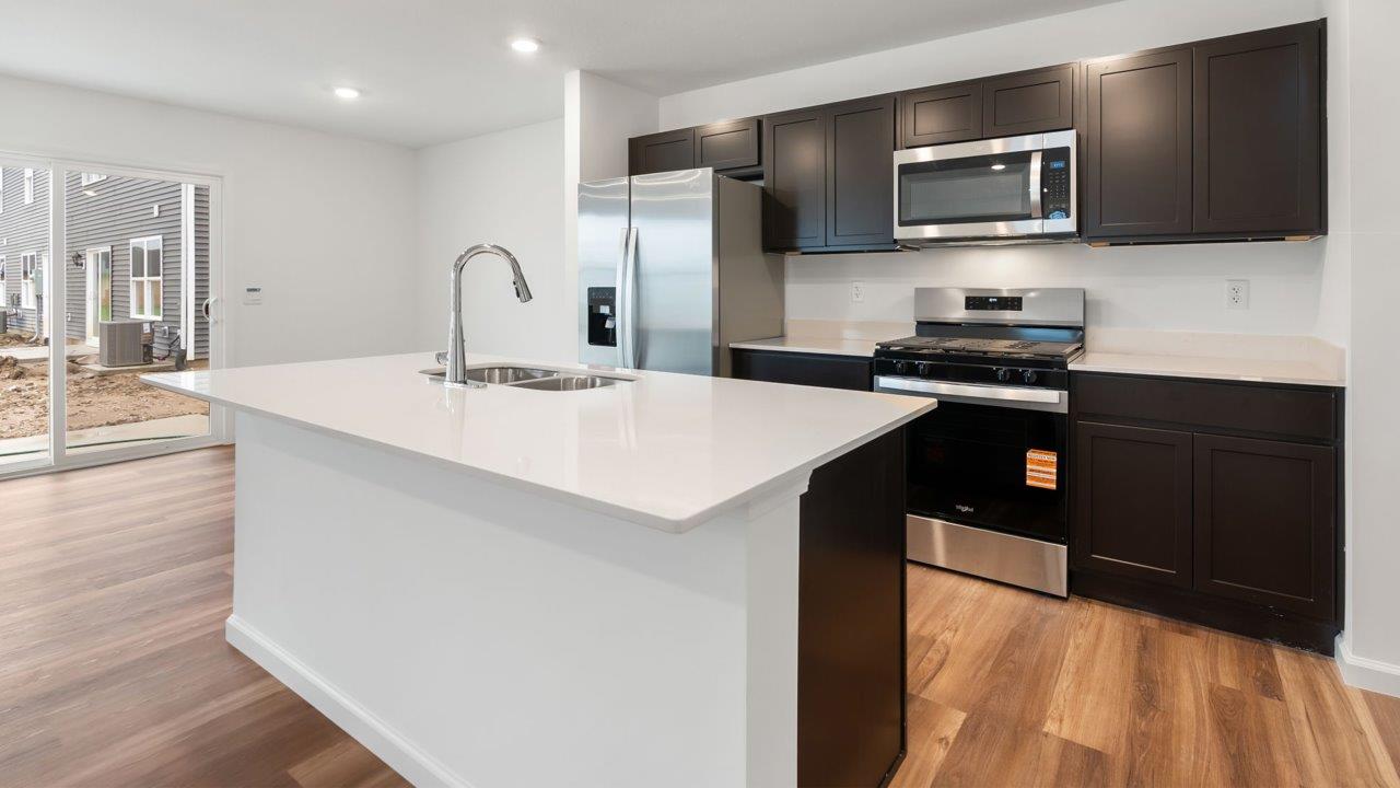 whispering pines portsmouth kitchen with sarsaparilla cabinets, quartz counters, island with bar seating, pantry, and stainless steel appliances