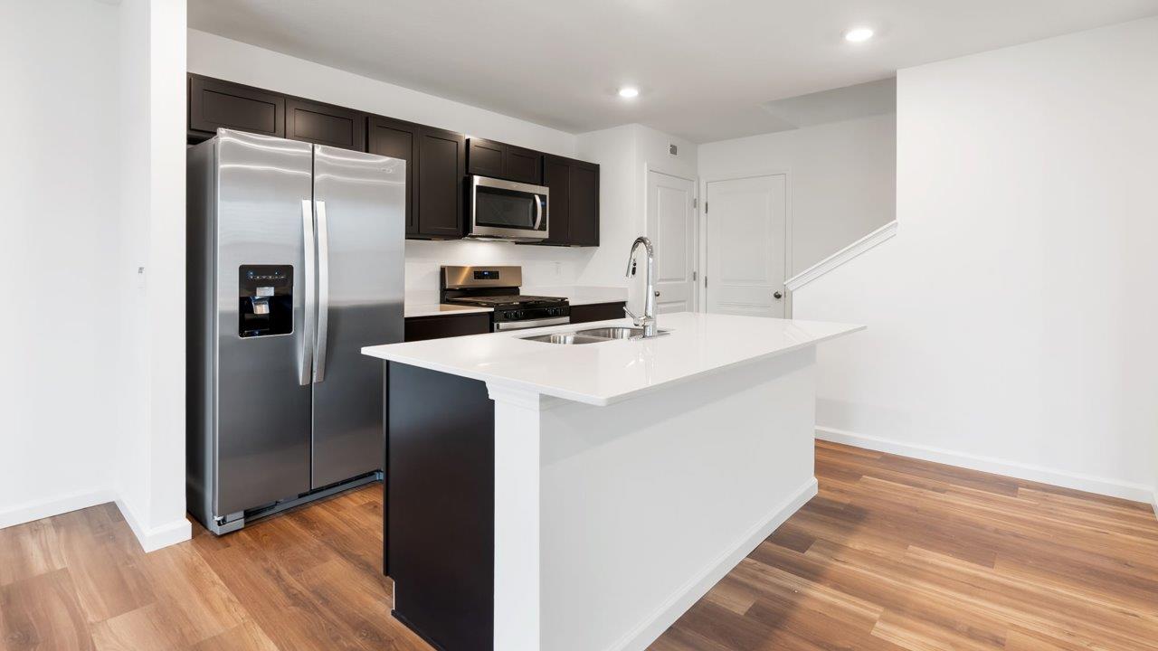 whispering pines portsmouth kitchen with sarsaparilla cabinets, quartz counters, island with bar seating, pantry, and stainless steel appliances