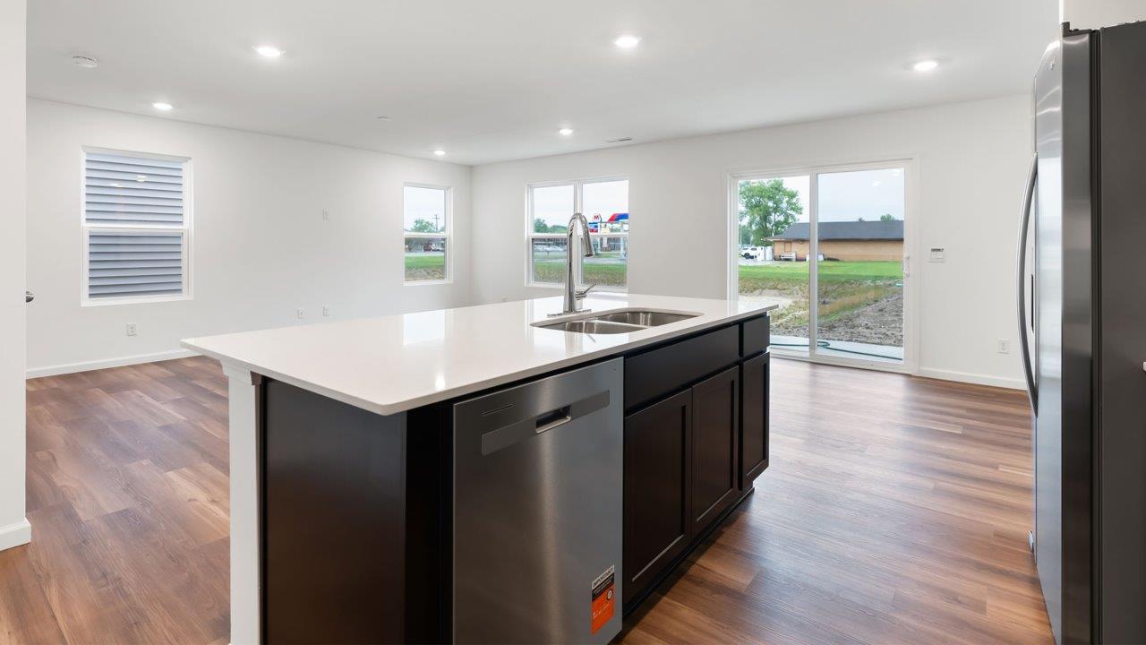 whispering pines portsmouth kitchen with sarsaparilla cabinets, quartz counters, island with bar seating, pantry, and stainless steel appliances