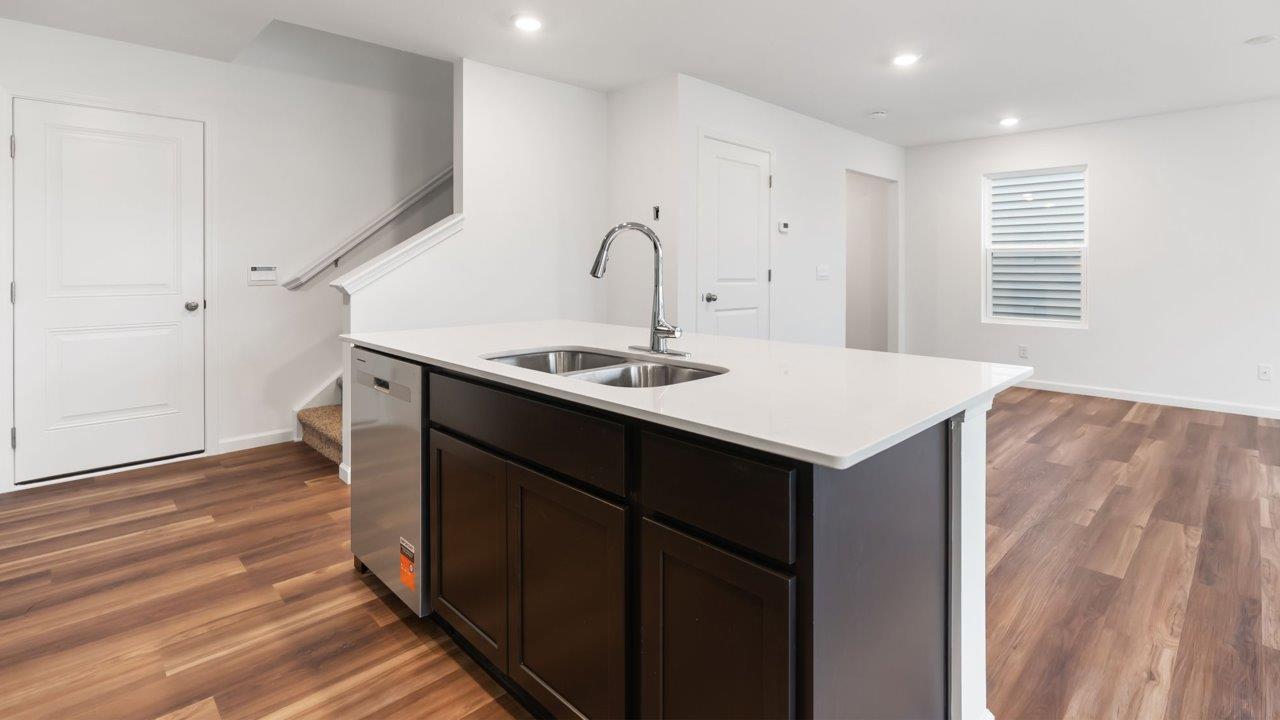 whispering pines portsmouth kitchen with sarsaparilla cabinets, quartz counters, island with bar seating, pantry, and stainless steel appliances