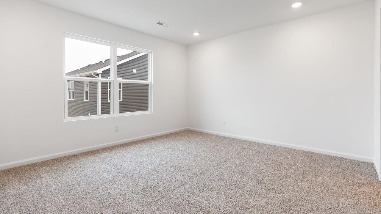 whispering pines portsmouth primary bedroom with beige carpet flooring, 2 windows, and ensuite bathroom and walk in closet