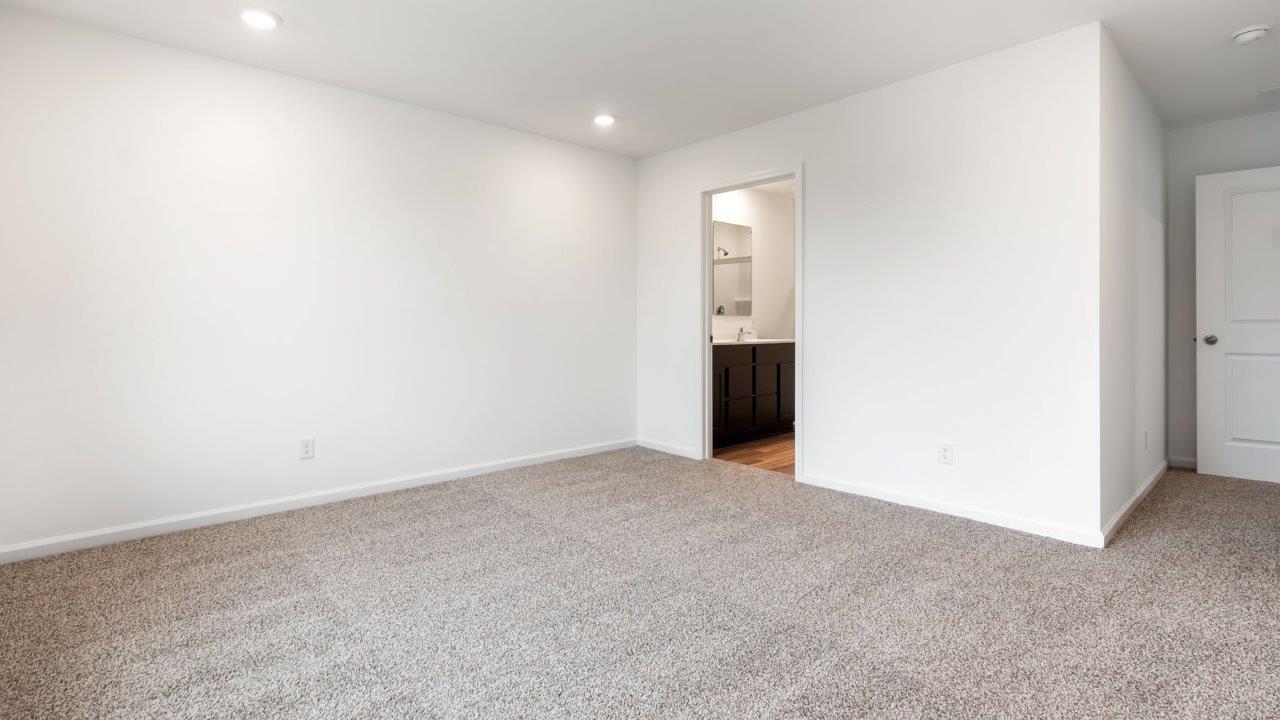 whispering pines portsmouth primary bedroom with beige carpet flooring, 2 windows, and ensuite bathroom and walk in closet