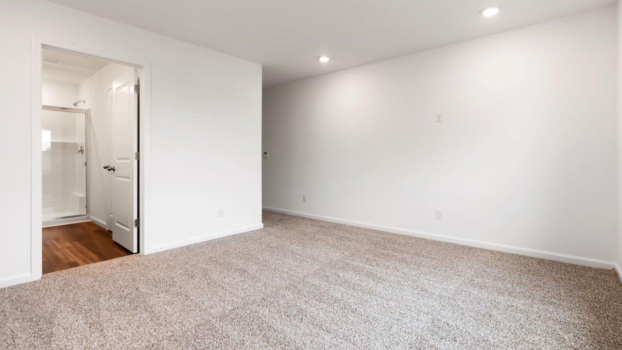 whispering pines portsmouth primary bedroom with beige carpet flooring, 2 windows, and ensuite bathroom and walk in closet