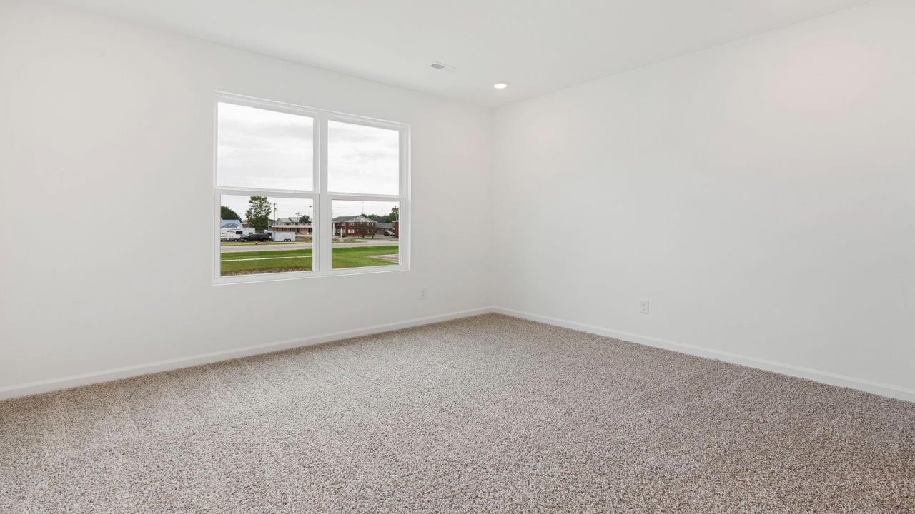 primary bedroom with carpet flooring, white walls, 2 windows, and ensuite bathroom and walk in closet