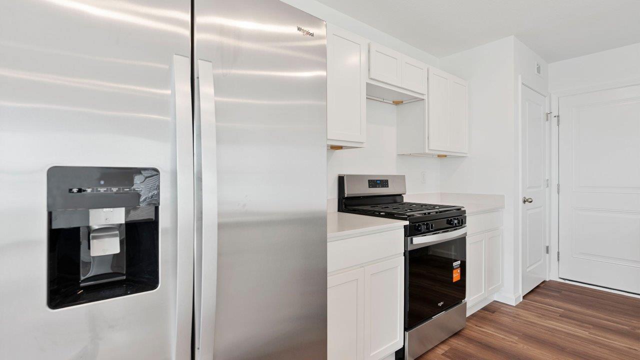 kitchen with quartz counters, white cabinets, stainless steel appliances, island, and pantry