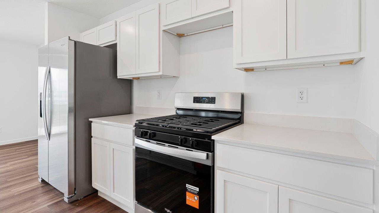 kitchen with quartz counters, white cabinets, stainless steel appliances, island, and pantry