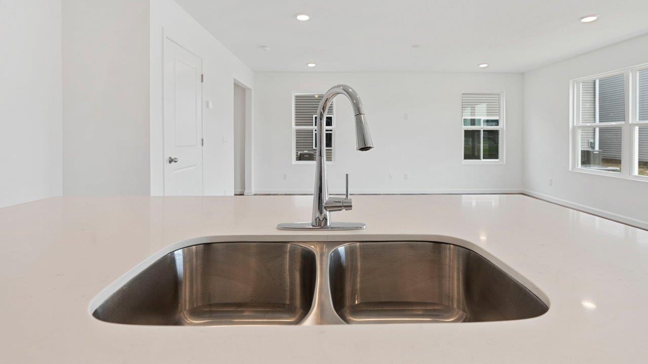 kitchen with quartz counters, white cabinets, stainless steel appliances, island, and pantry