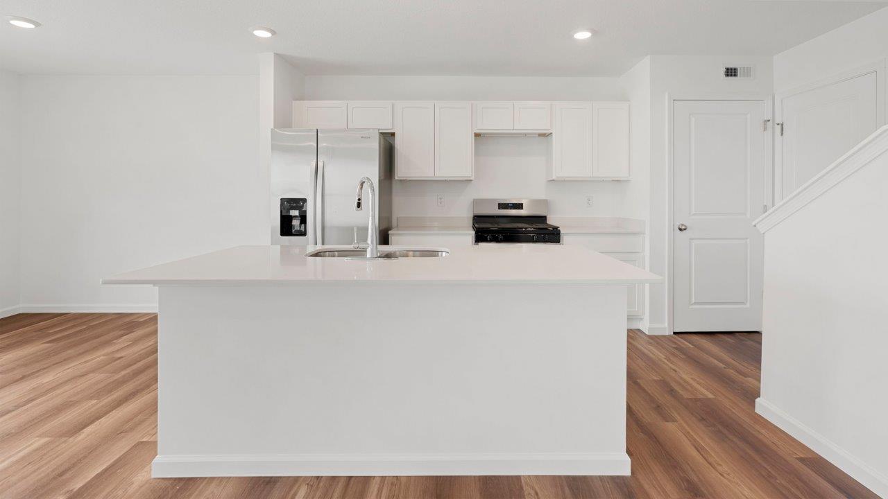 kitchen with quartz counters, white cabinets, stainless steel appliances, island, and pantry