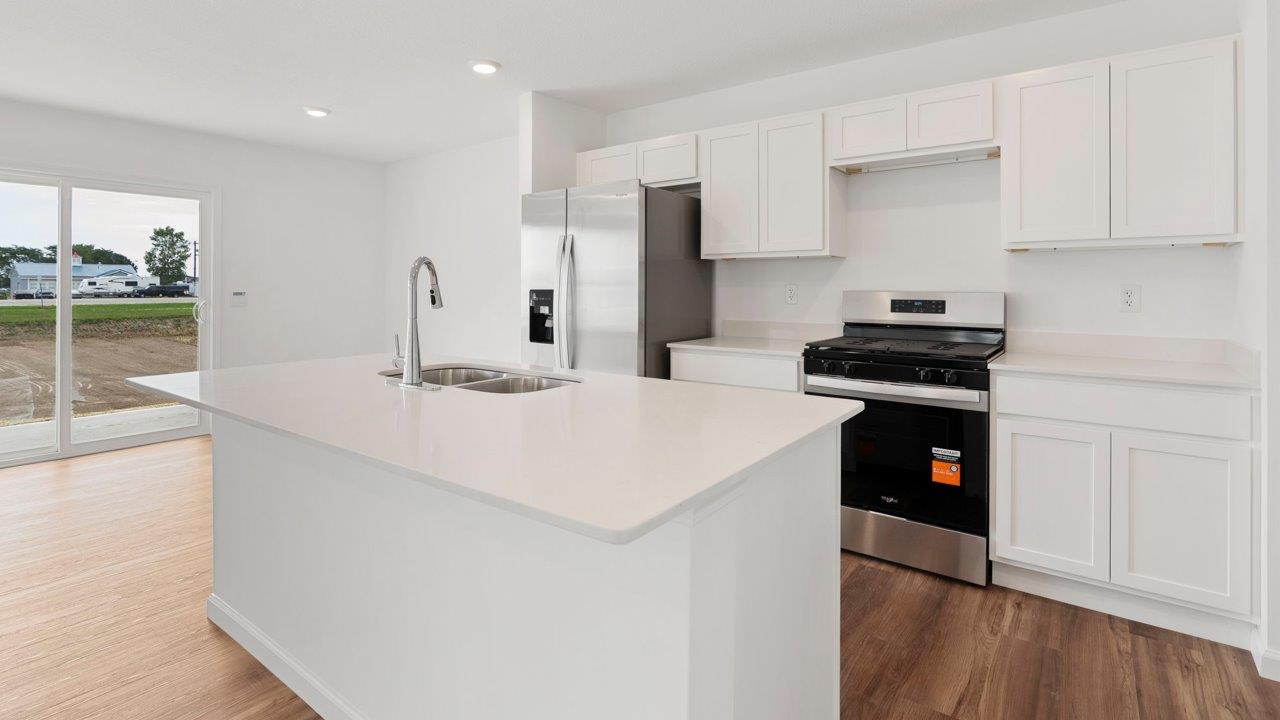 kitchen with quartz counters, white cabinets, stainless steel appliances, island, and pantry