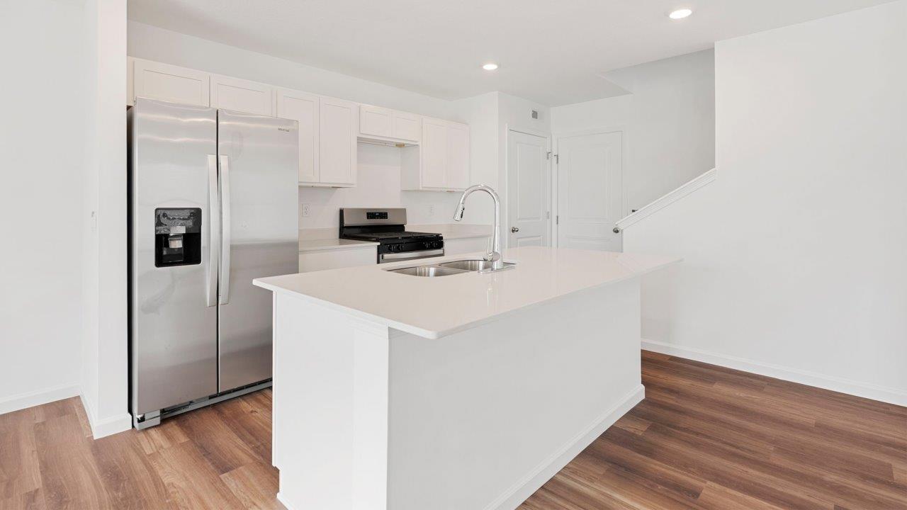 kitchen with quartz counters, white cabinets, stainless steel appliances, island, and pantry
