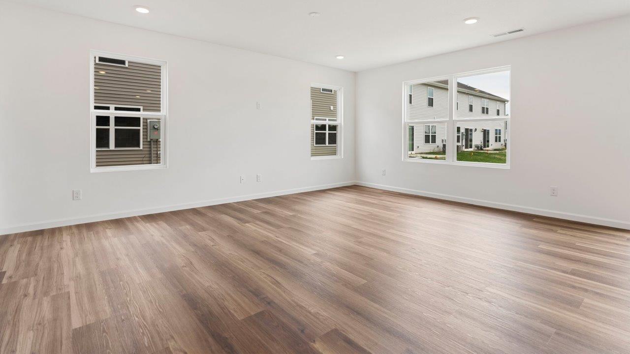 open layout living room with 4 windows, luxury vinyl plank flooring, and white walls