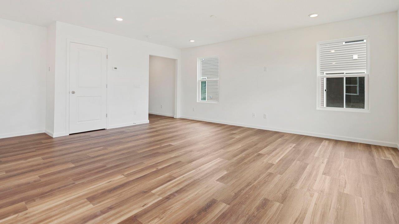 open layout living room with 4 windows, luxury vinyl plank flooring, and white walls