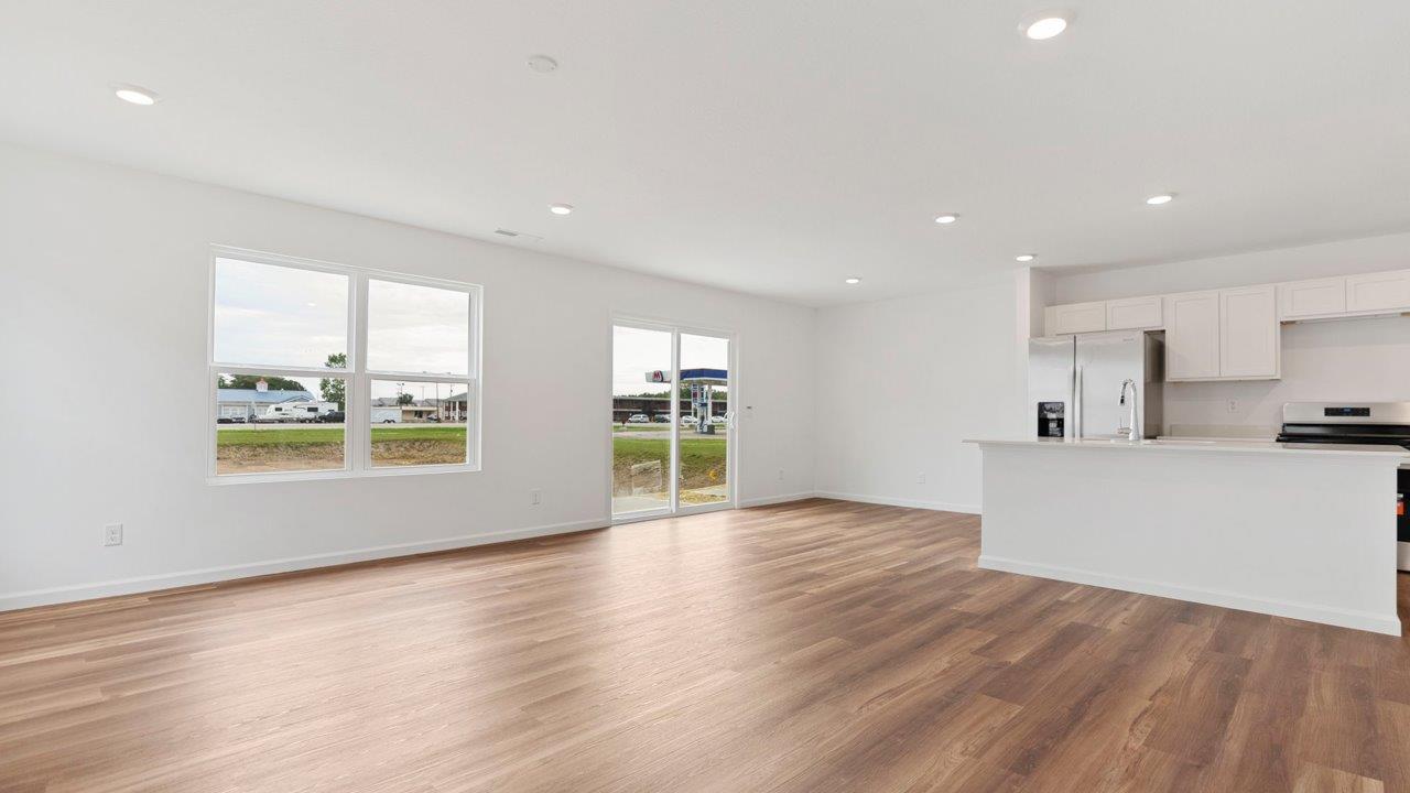 open layout living room with 4 windows, luxury vinyl plank flooring, and white walls