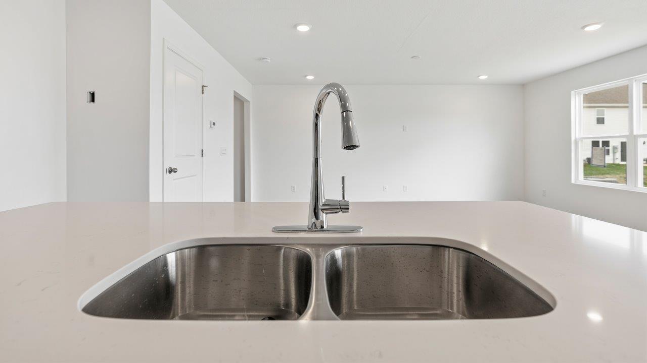 kitchen with sarsaparilla cabinets, quartz countertops, stainless steel appliances, pantry, and island