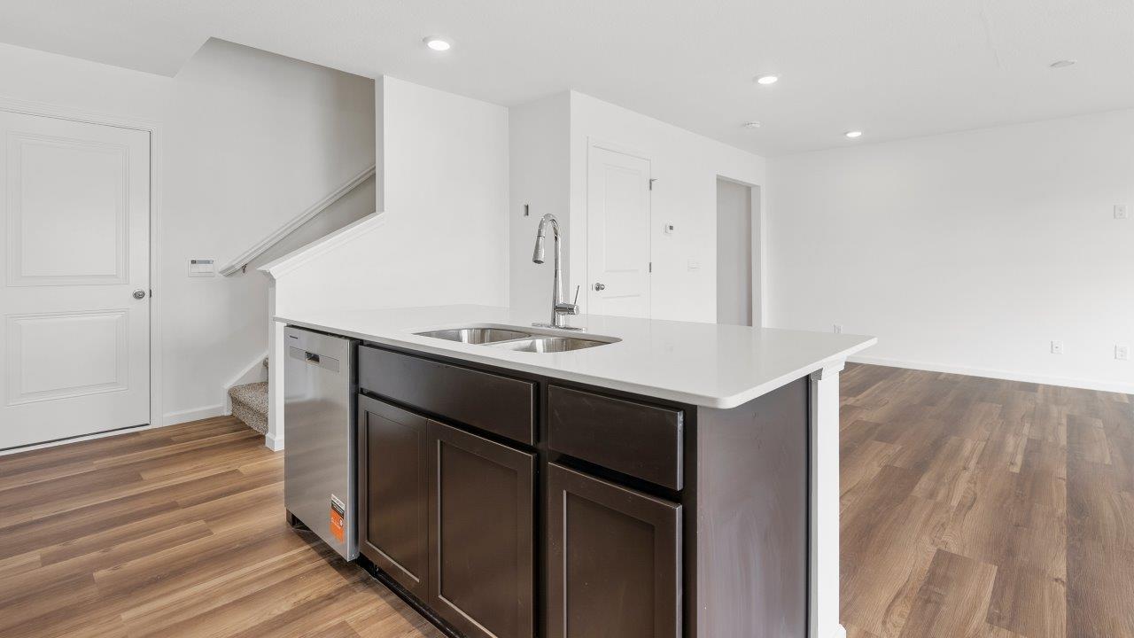 kitchen with sarsaparilla cabinets, quartz countertops, stainless steel appliances, pantry, and island