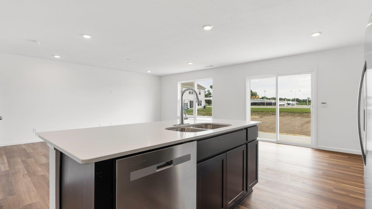 kitchen with sarsaparilla cabinets, quartz countertops, stainless steel appliances, pantry, and island