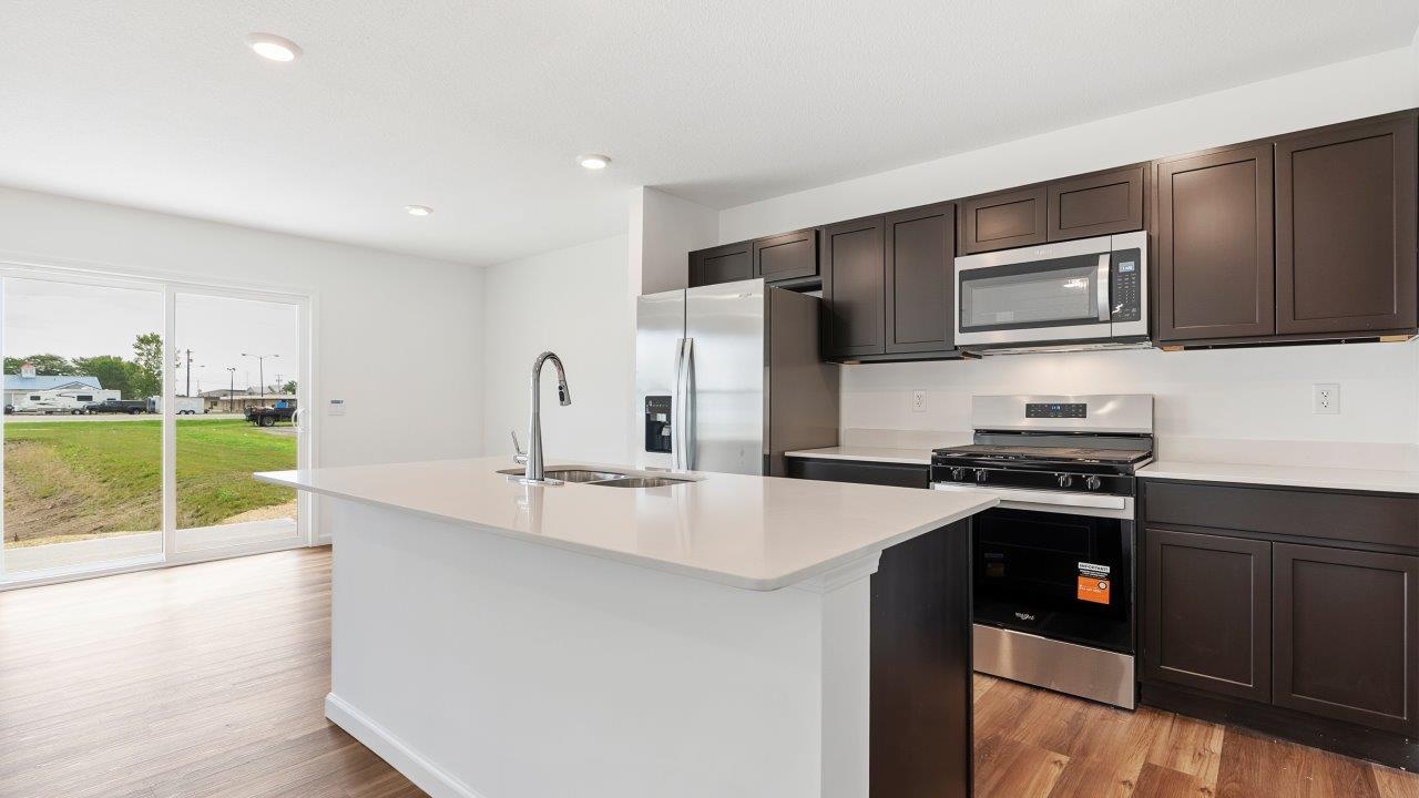 kitchen with sarsaparilla cabinets, quartz countertops, stainless steel appliances, pantry, and island