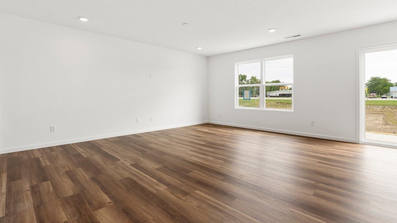 living room with mohawk luxury vinyl plank flooring, white walls, and 2 windows