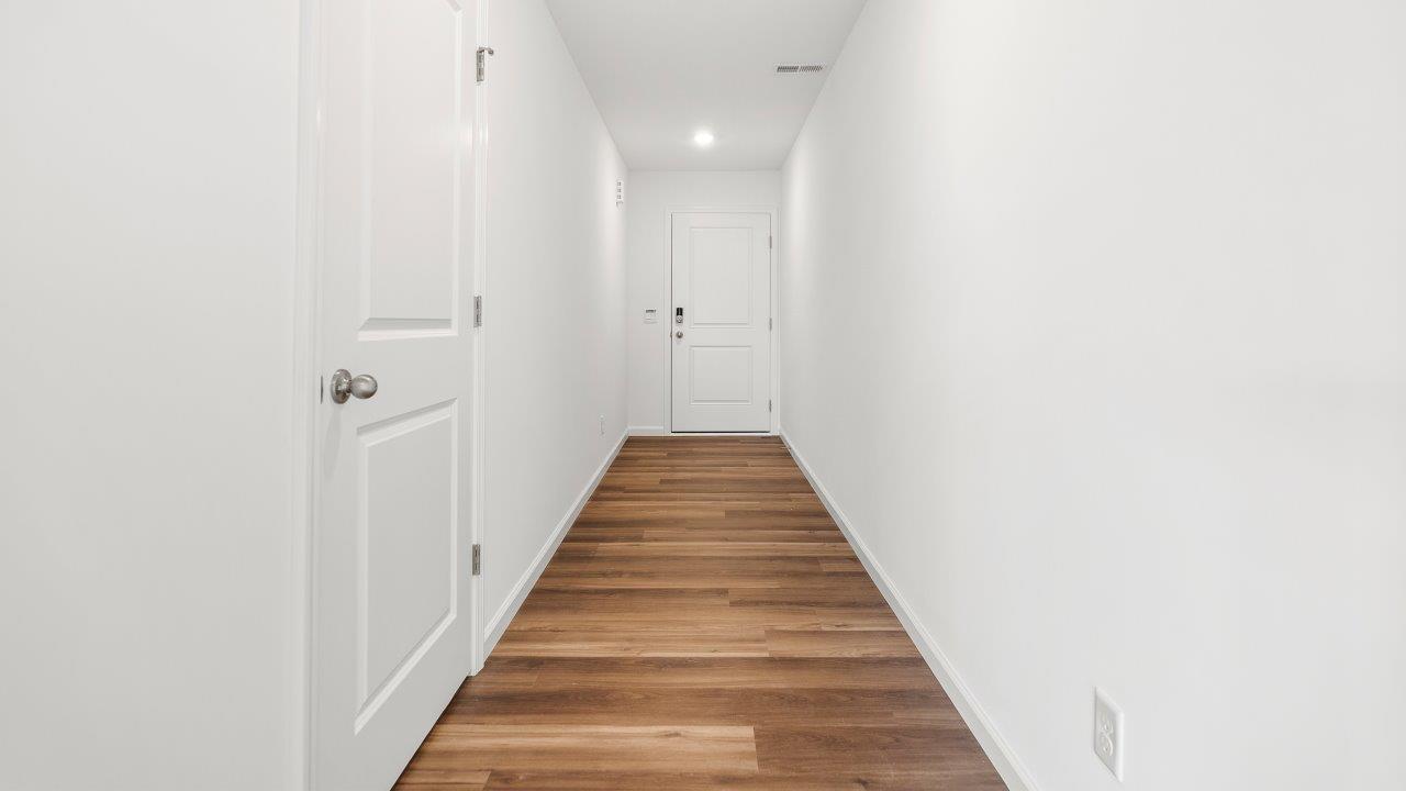 front door and foyer with white walls, lvp flooring, and powder room