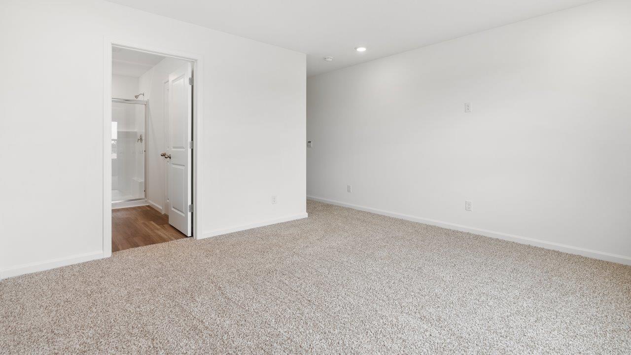 primary bedroom with carpet flooring, ensuite bathroom, and walk in closet