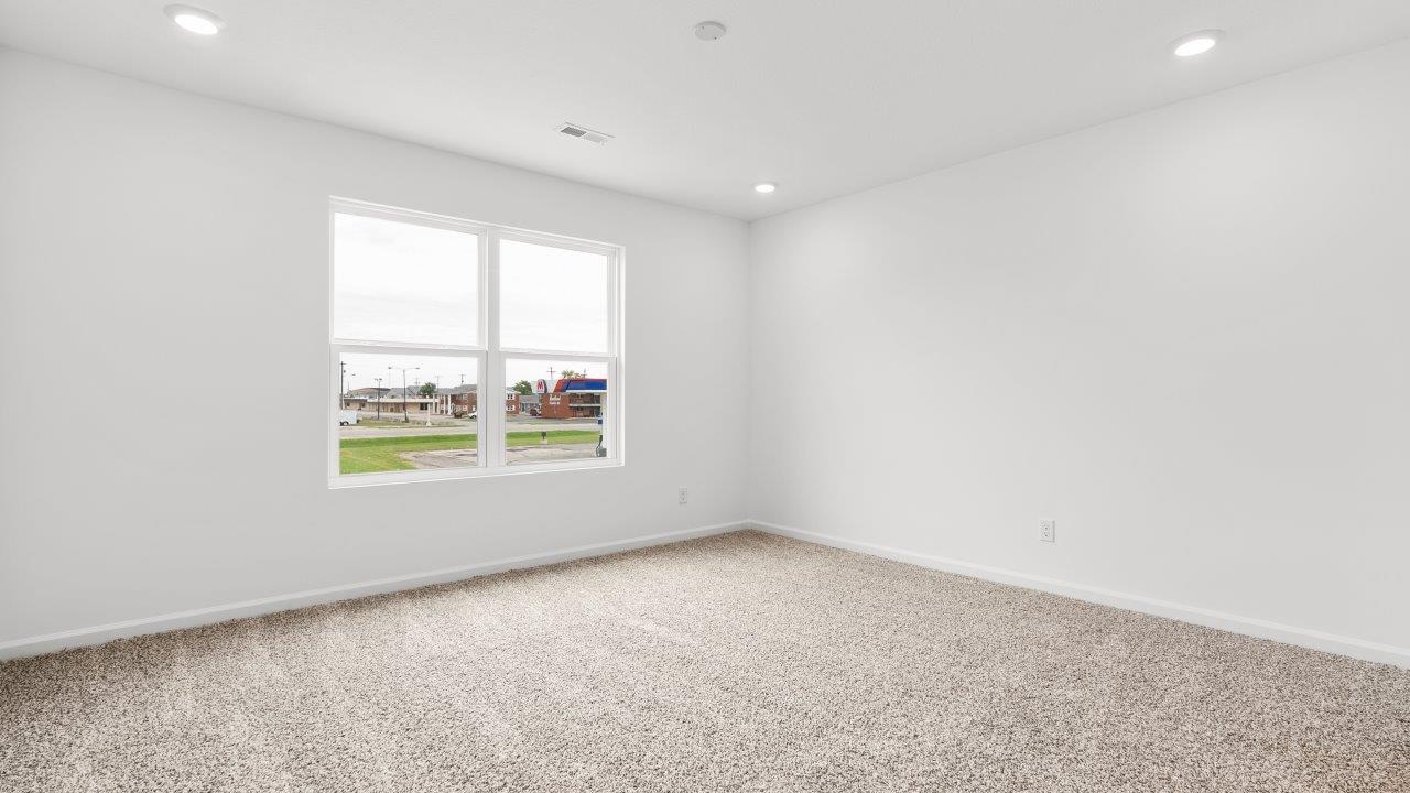 primary bedroom with carpet flooring, ensuite bathroom, and walk in closet