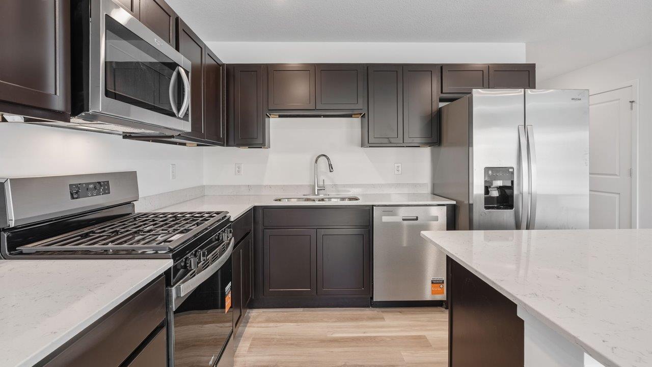whispering pines pearson - kitchen with sarsaparilla, stainless steel appliances, quartz countertops, and center island