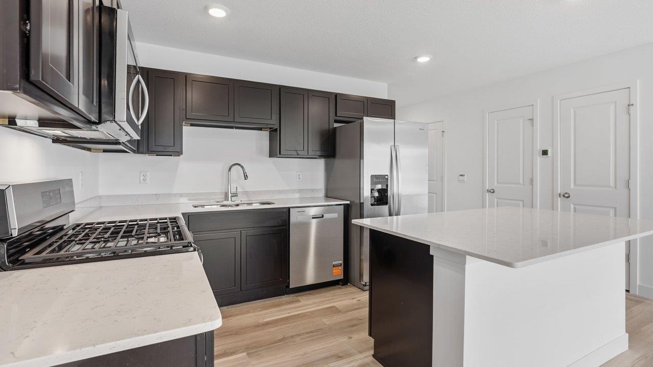 whispering pines pearson - kitchen with sarsaparilla, stainless steel appliances, quartz countertops, and center island