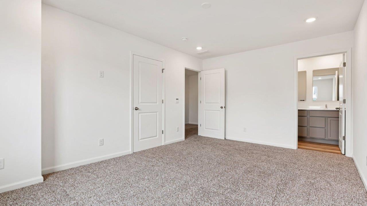 whispering pines pearson primary bedroom with carpet flooring, 2 windows, and ensuite bathroom and walk in closet