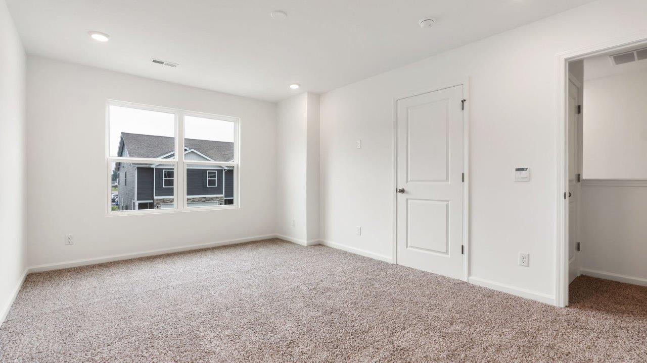 whispering pines pearson primary bedroom with carpet flooring, 2 windows, and ensuite bathroom and walk in closet
