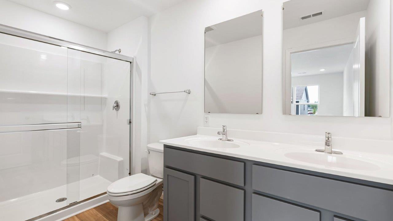 whispering pines pearson primary bedroom full bathroom with dual sink vanity and walk in shower