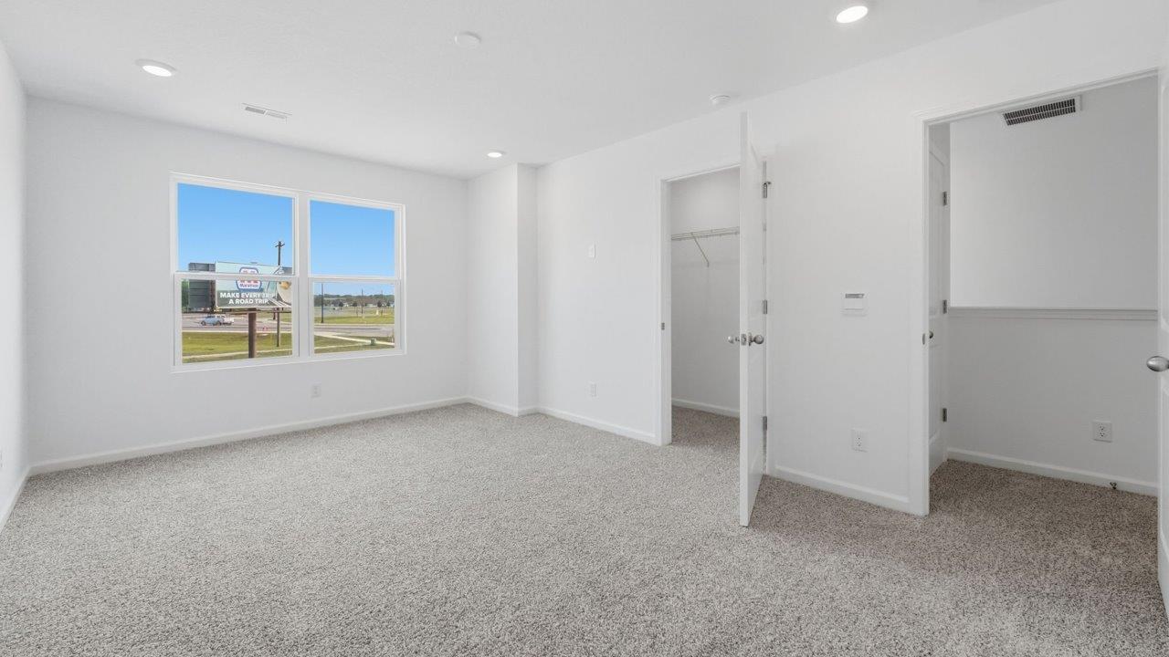 whispering pines pearson primary bedroom with beige carpet, white walls, and ensuite bathroom and walk in closet