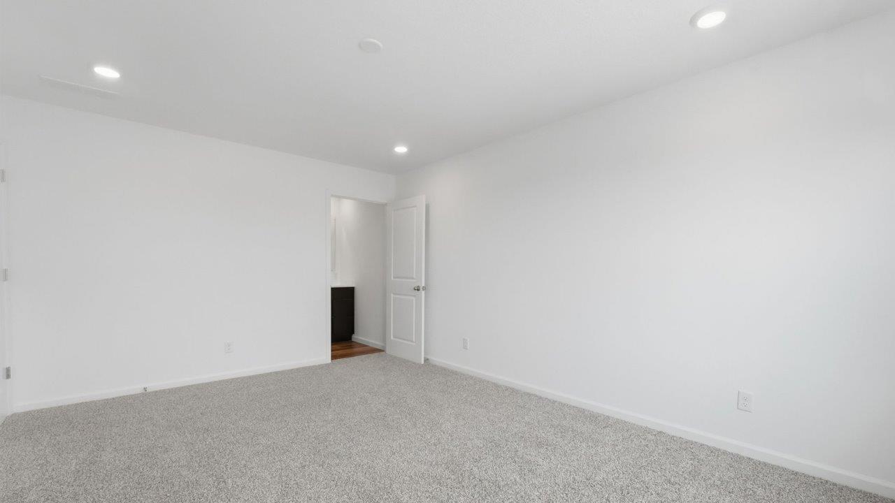 whispering pines pearson primary bedroom with beige carpet, white walls, and ensuite bathroom and walk in closet