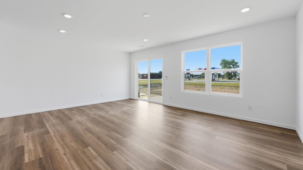whispering pines pearson open layout living room with white walls, lvp flooring, and sliding glass door to backyard patio