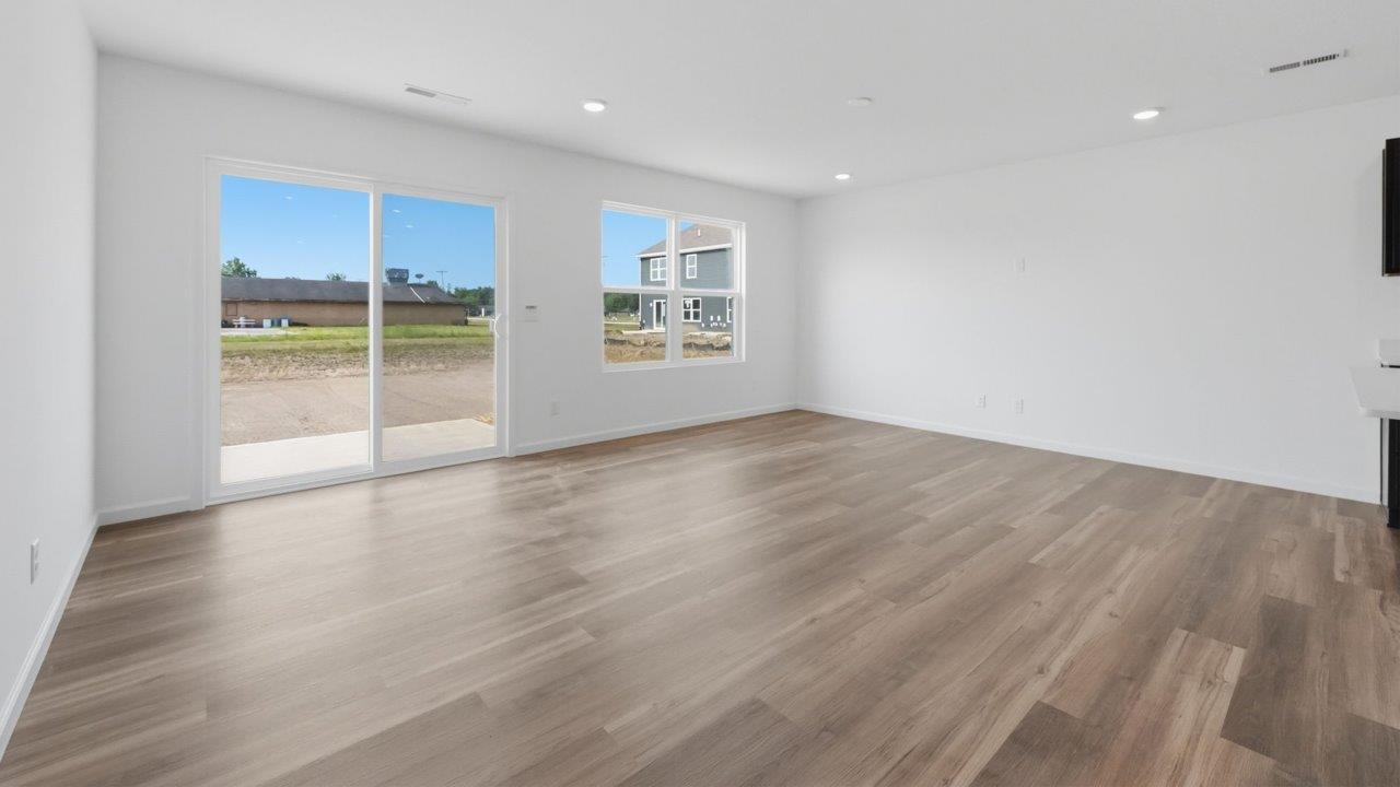 whispering pines pearson open layout living room with white walls, lvp flooring, and sliding glass door to backyard patio