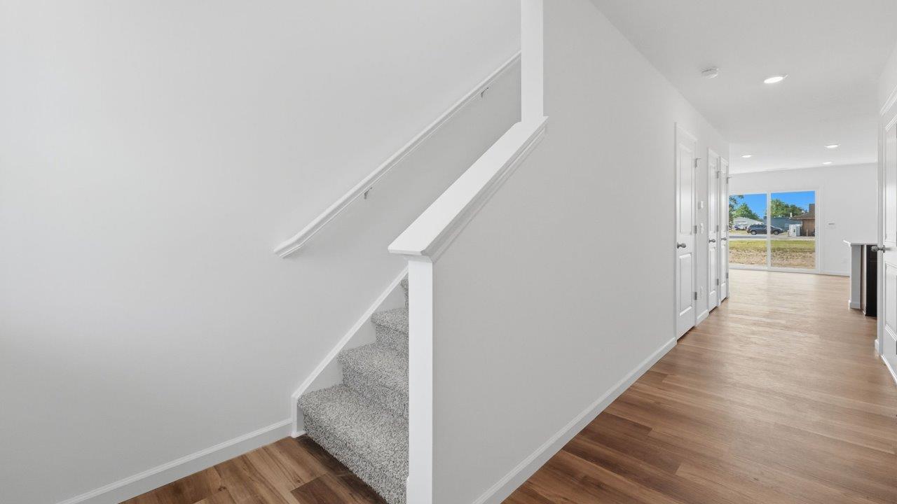 whispering pines foyer with lvp and staircase with beige carpet flooring