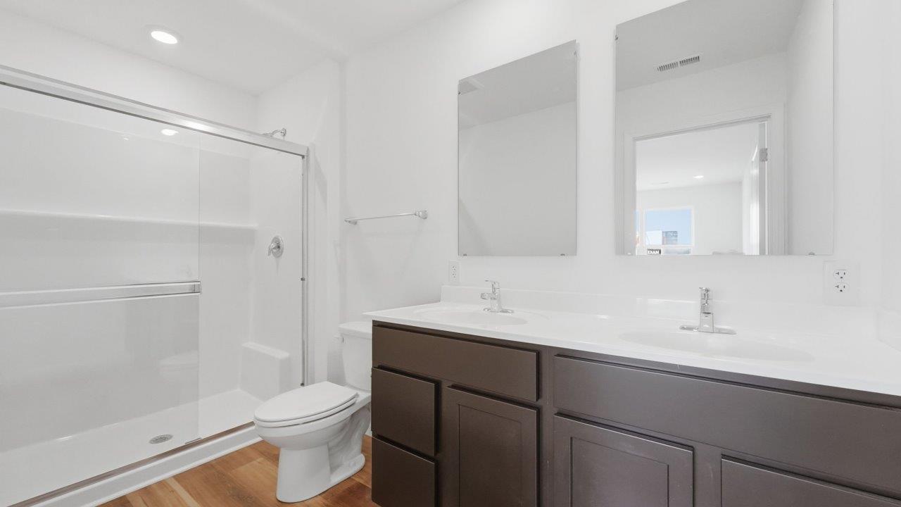 whispering pines pearson primary ensuite bathroom with dual sink vanity, lvp flooring, and walk in shower