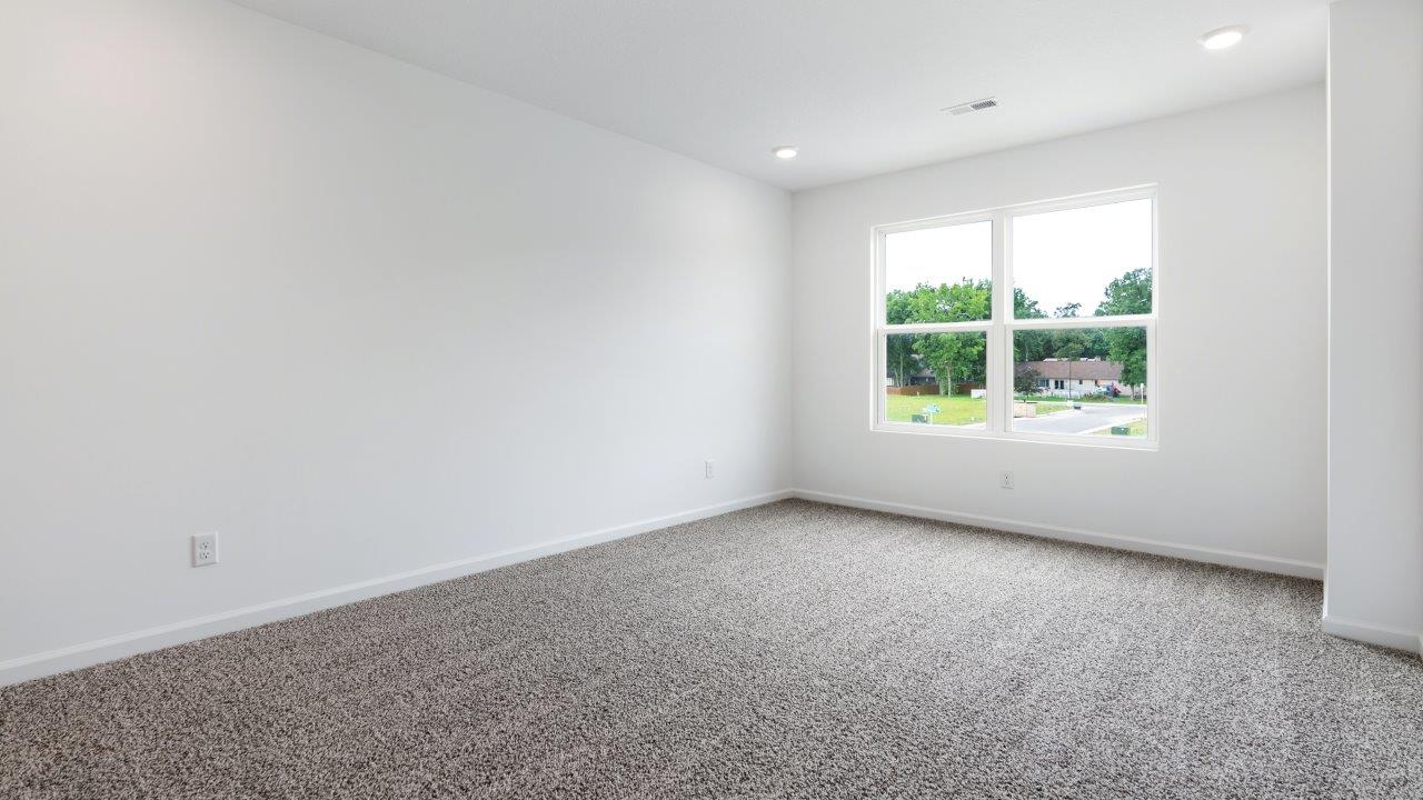 primary bedroom with carpet flooring, 2 windows, and ensuite bathroom and walk in closet