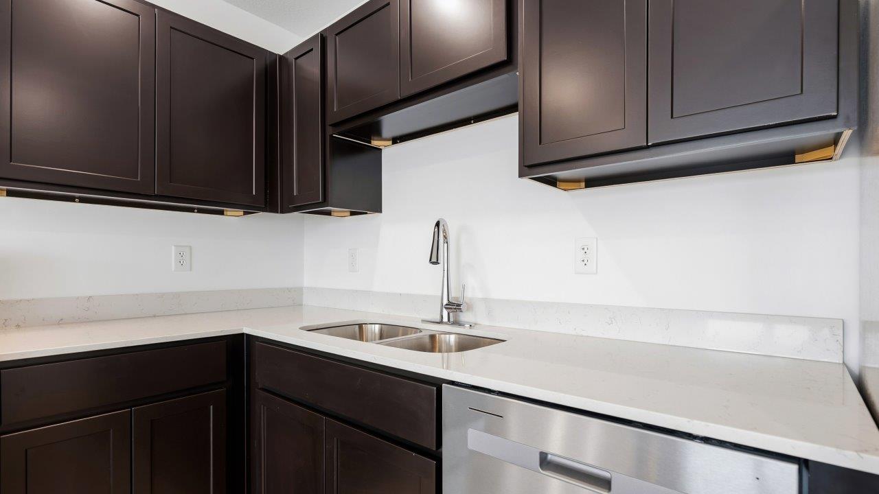 kitchen with dark brown sarsaparilla cabinets, stainless steel appliances, quartz countertops