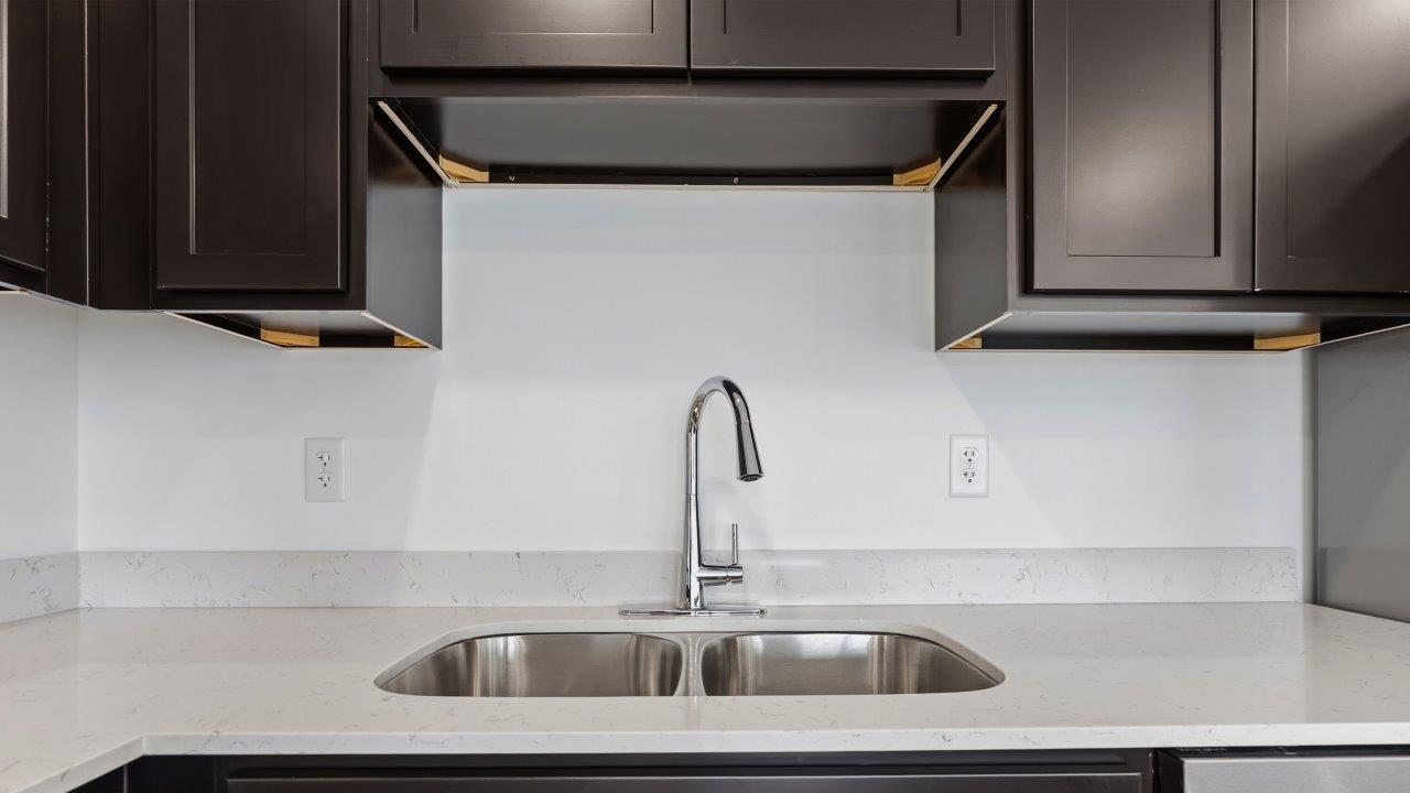 kitchen with dark brown sarsaparilla cabinets, stainless steel appliances, quartz countertops