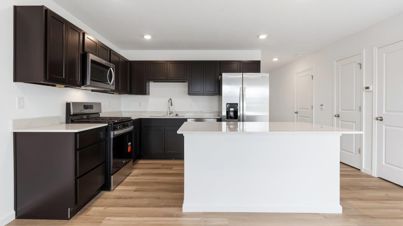 kitchen with dark brown sarsaparilla cabinets, stainless steel appliances, quartz countertops