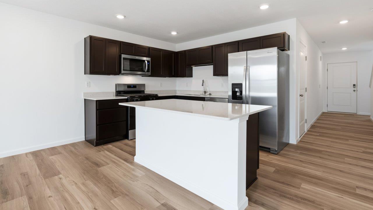 kitchen with dark brown sarsaparilla cabinets, stainless steel appliances, quartz countertops