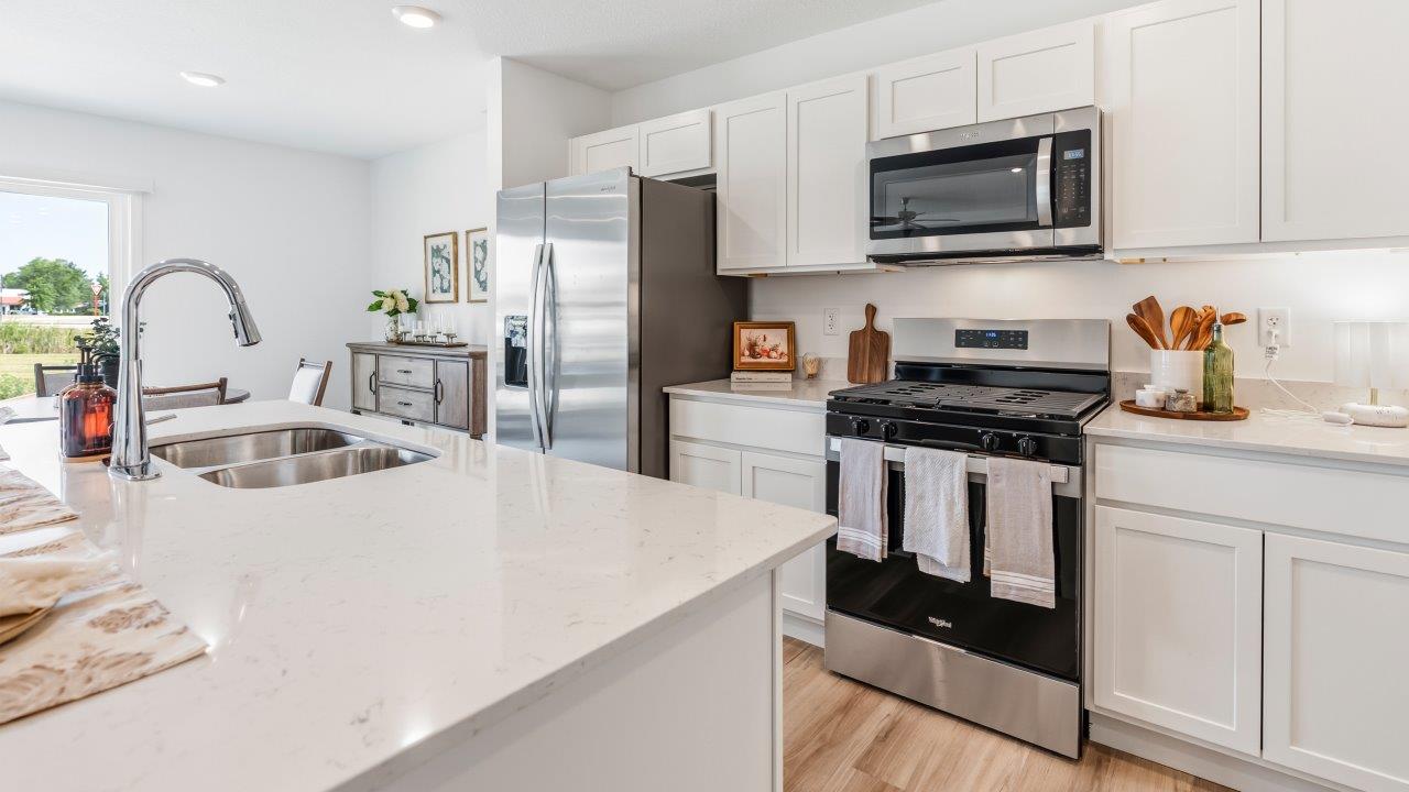 whispering pines pattison plan interior model home - kitchen with appliances, quartz countertops, and center island