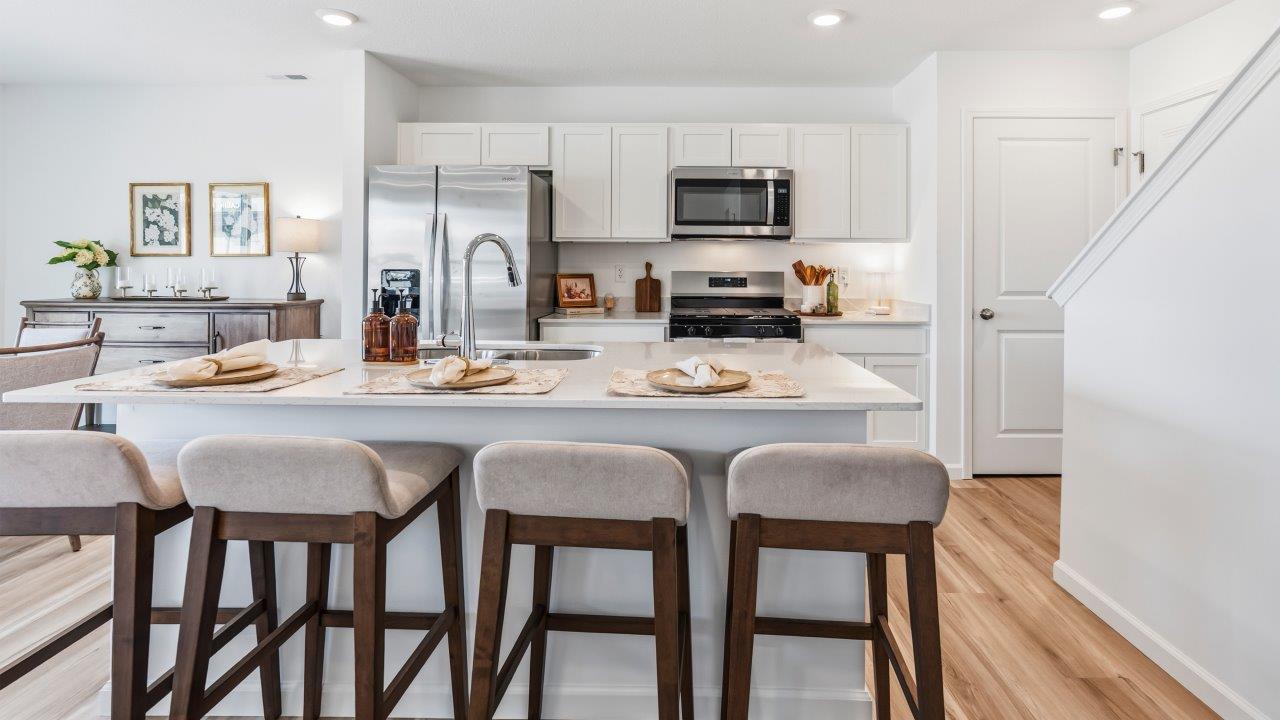 whispering pines pattison plan interior model home - kitchen with appliances, quartz countertops, and center island