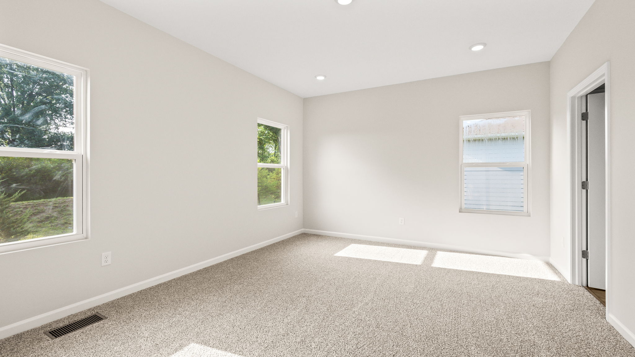 Carpeted primary bedroom with three windows