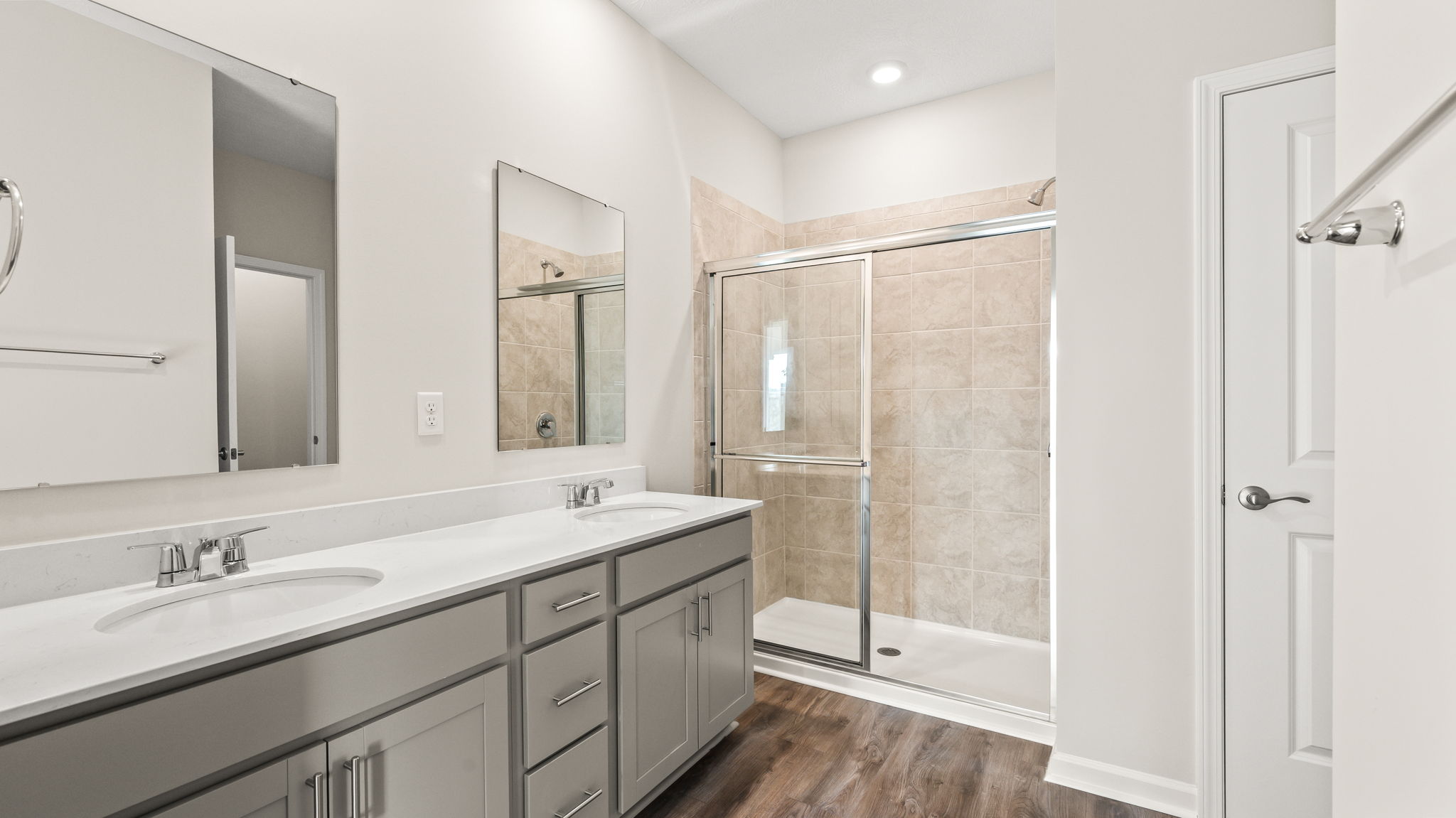 Wide image of entire bathroom with dual-sink vanities and shower