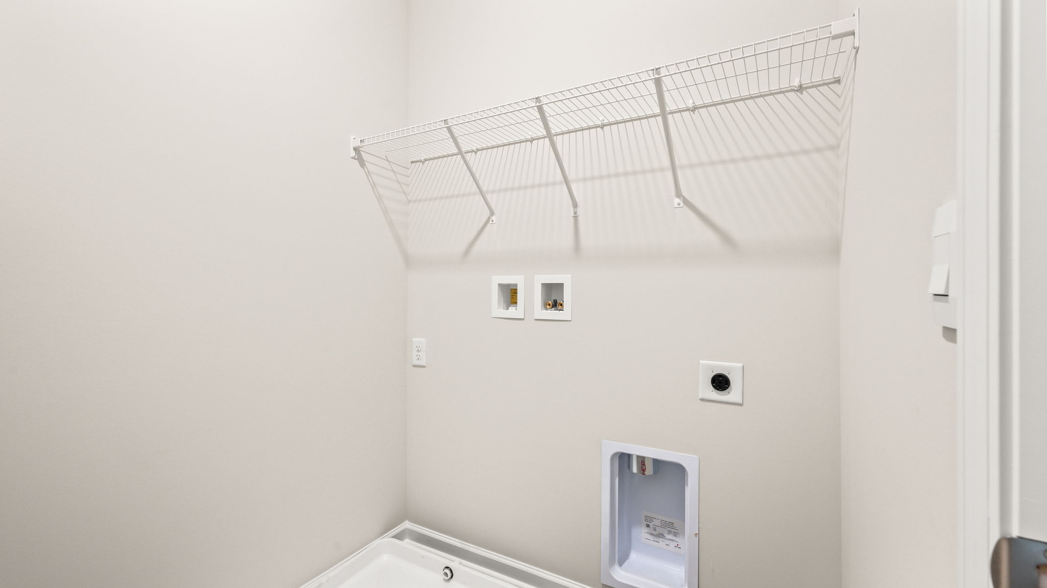 Laundry area with washer/dryer inlets and wire rack shelving