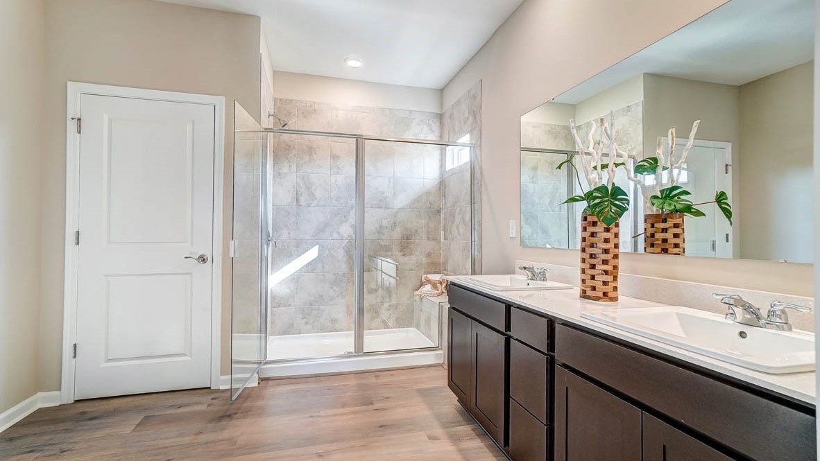 private bathroom off primary with dual vanity sinks, large walk in shower, and storage closet.