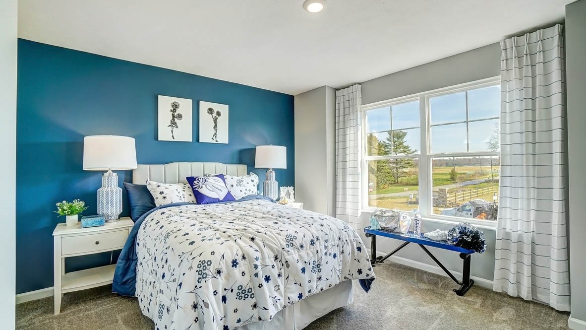 bedroom with large bed, blue bench and cheerleading decorations.
