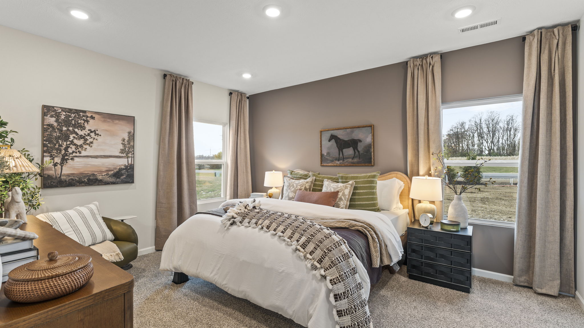 Primary bedroom with cottage style bedding and nature themed art on walls.